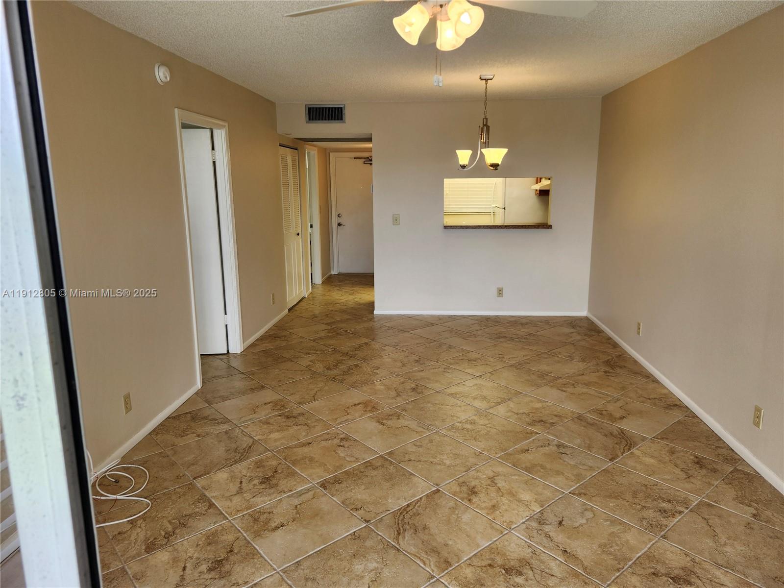 9450 Poinciana Place, Unit 205 Davie, FL 33324 - Photo 2 of 9 an empty room with kitchen and chandelier fan