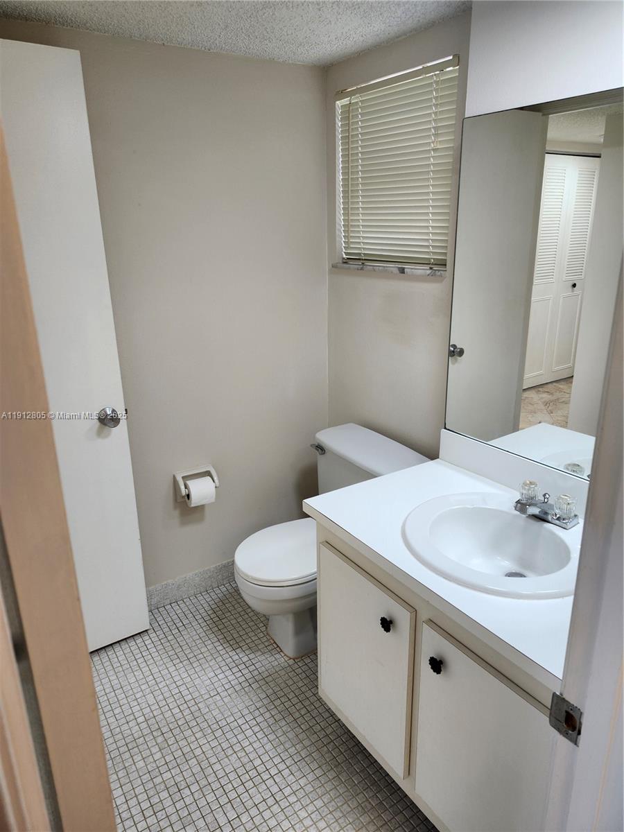 9450 Poinciana Place, Unit 205 Davie, FL 33324 - Photo 6 of 9 a bathroom with a sink a toilet and a mirror
