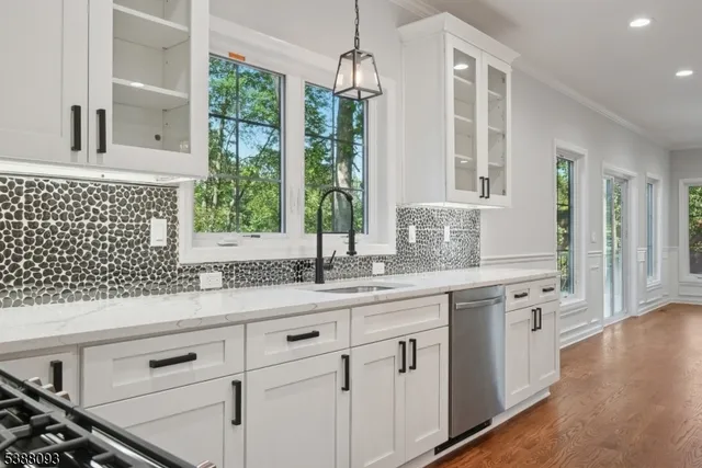 a kitchen with granite countertop white cabinets white appliances with a sink and wooden floor