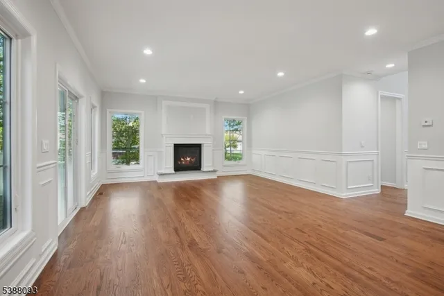 an empty room with wooden floor fireplace and windows
