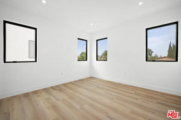 a view of an empty room with wooden floor and a painting on the wall