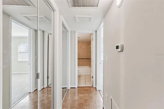 an empty room with a chandelier fan and closet area