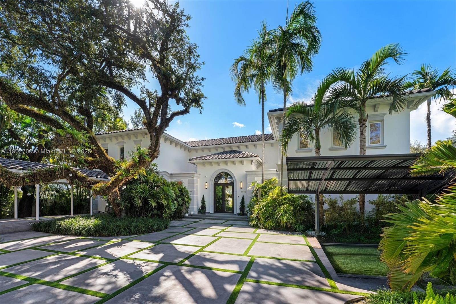 5770 Southwest 100th Street Pinecrest, FL 33156 - Photo 6 of 57 a view of a white house with a yard and potted plants