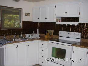 345 Reuben Branch Road Maggie Valley, NC 28751 - Photo 8 of 12 a kitchen with granite countertop white cabinets and black appliances