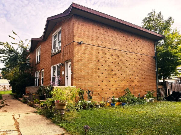 a view of a house with brick walls and a yard with plants
