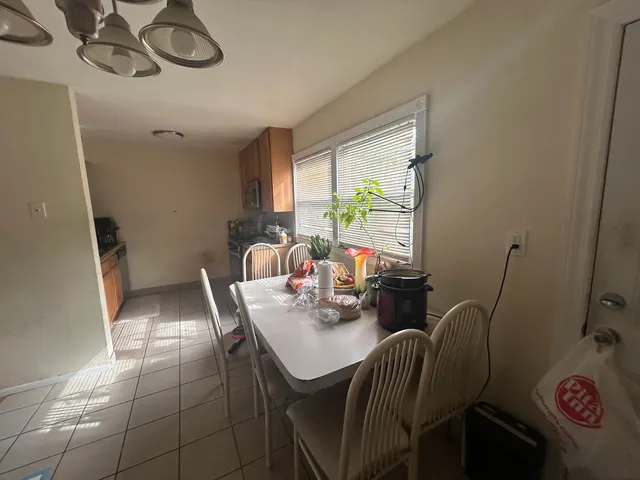 a view of a dining room with furniture a potted plant and a window