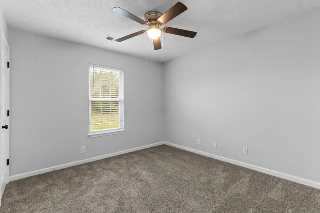 an empty room with a window and a fan