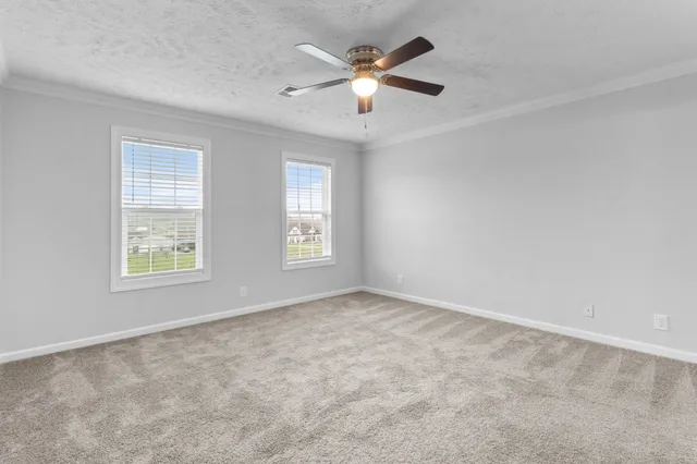 an empty room with windows and ceiling fan