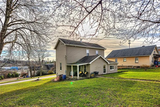 a view of a house with a big yard and large trees