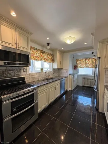 a kitchen with stainless steel appliances granite countertop a stove a sink and a microwave