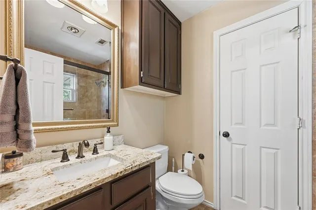 a bathroom with a granite countertop sink toilet a mirror and shower