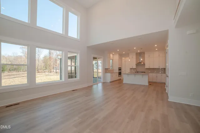 a view of an empty room with a kitchen view and a window