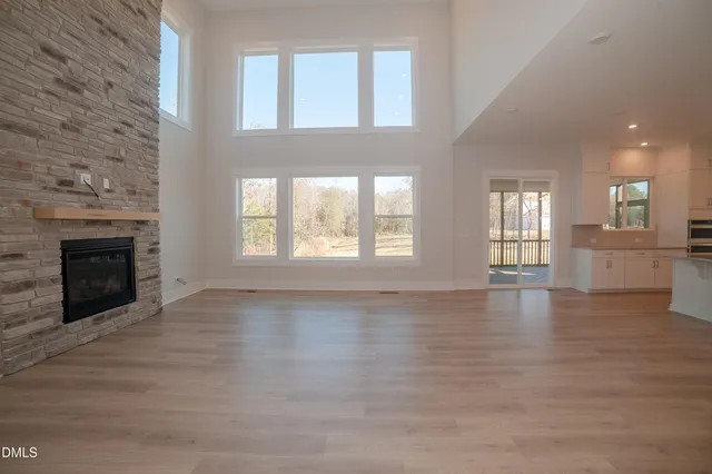 an empty room with wooden floor fireplace and windows