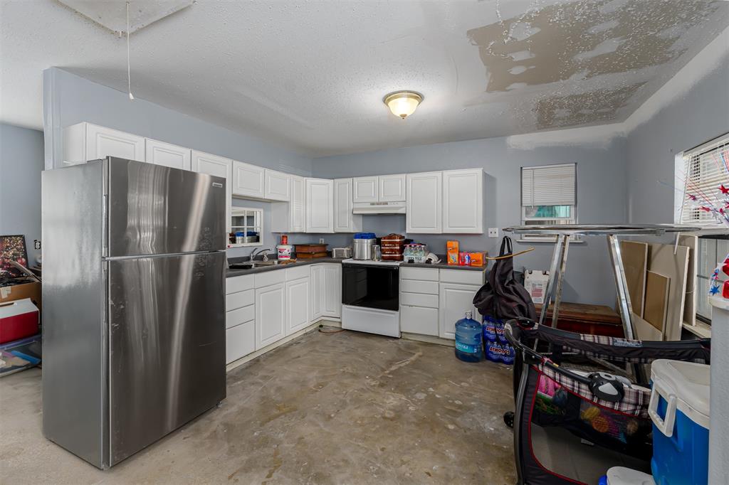 601 Houston School Road Red Oak, TX 75154 - Photo 23 of 32 Kitchen with freestanding refrigerator, electric range oven, unfinished concrete floors, a sink, and under cabinet range hood