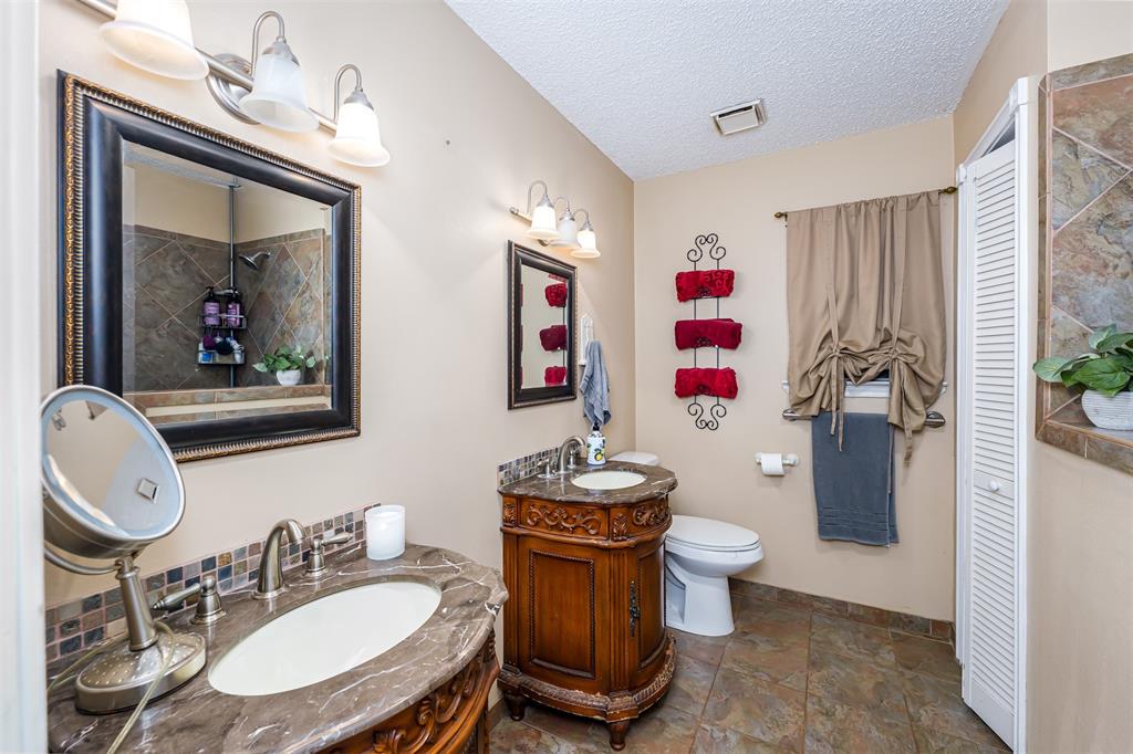 601 Houston School Road Red Oak, TX 75154 - Photo 8 of 32 Bathroom with a closet, baseboards, stone finish floors, two vanities, and a textured ceiling