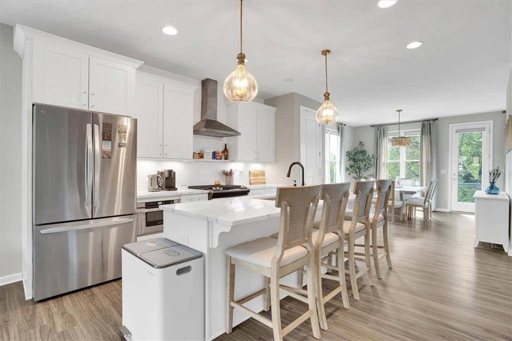 775 Hamilton Circle Southeast Atlanta, GA 30312 - Photo 10 of 24 a kitchen with stainless steel appliances a refrigerator a stove a kitchen island a dining table and chairs with wooden floor