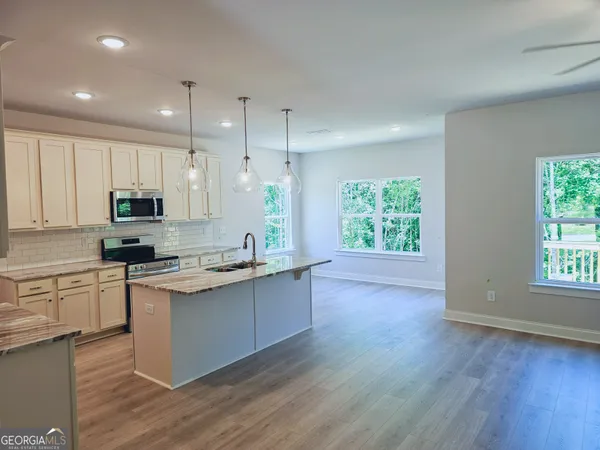 a kitchen with stainless steel appliances granite countertop wooden floors a stove a sink and a window