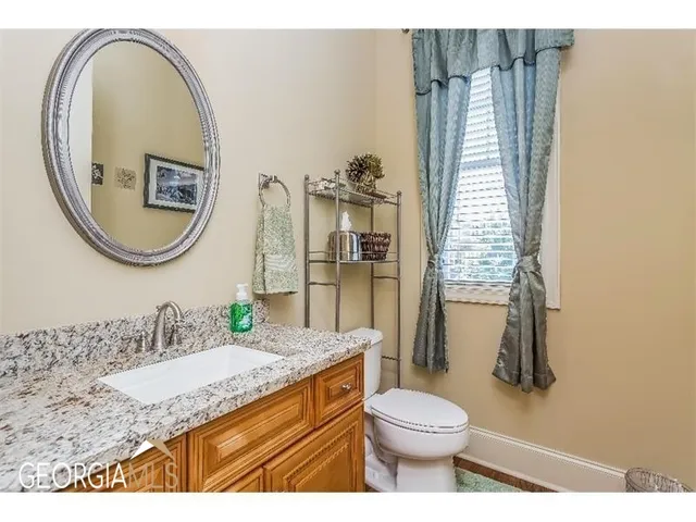 a bathroom with a granite countertop toilet a sink and a mirror