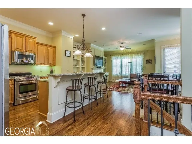 a open kitchen with stainless steel appliances granite countertop a stove a refrigerator a kitchen island a stove and a wooden floors