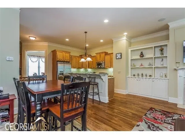 a dining hall with stainless steel appliances a dining table wooden floor and a kitchen view