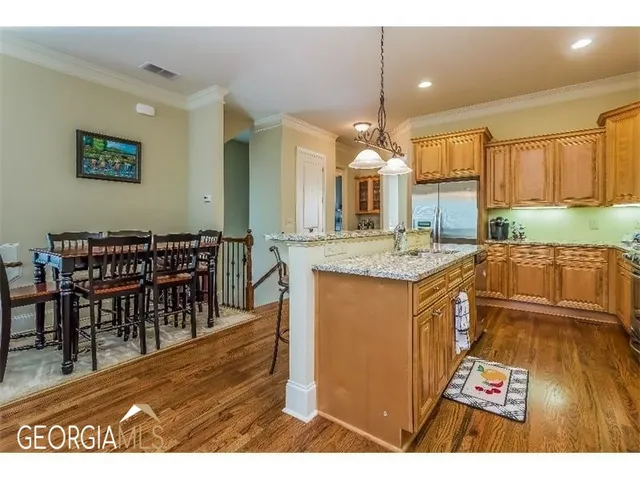 a open kitchen with stainless steel appliances granite countertop a stove a sink a dining table and chairs with wooden floor