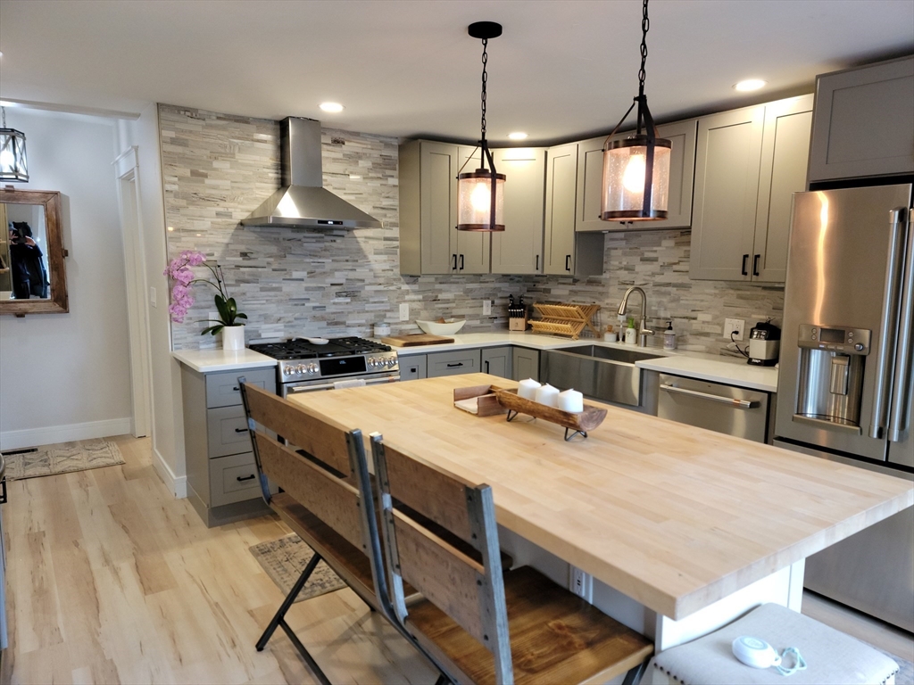 76 Milk Street, Unit 1 Westborough, MA 01581 - Photo 3 of 19 a kitchen with kitchen island a stove a sink a refrigerator and chairs