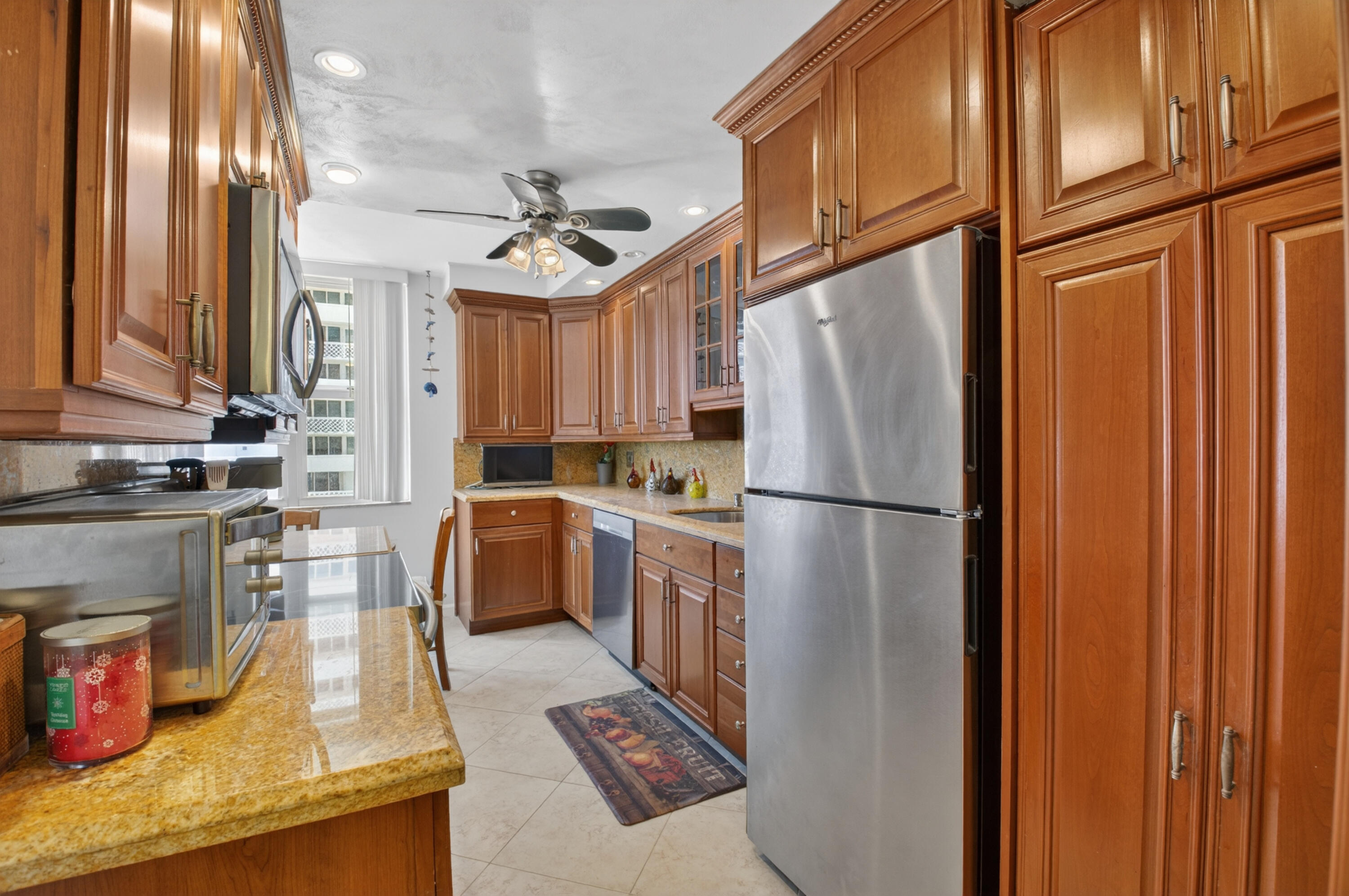 1180 South Ocean Boulevard, Unit 5C Boca Raton, FL 33432 - Photo 23 of 43 a kitchen with stainless steel appliances granite countertop a refrigerator a sink and wooden cabinets