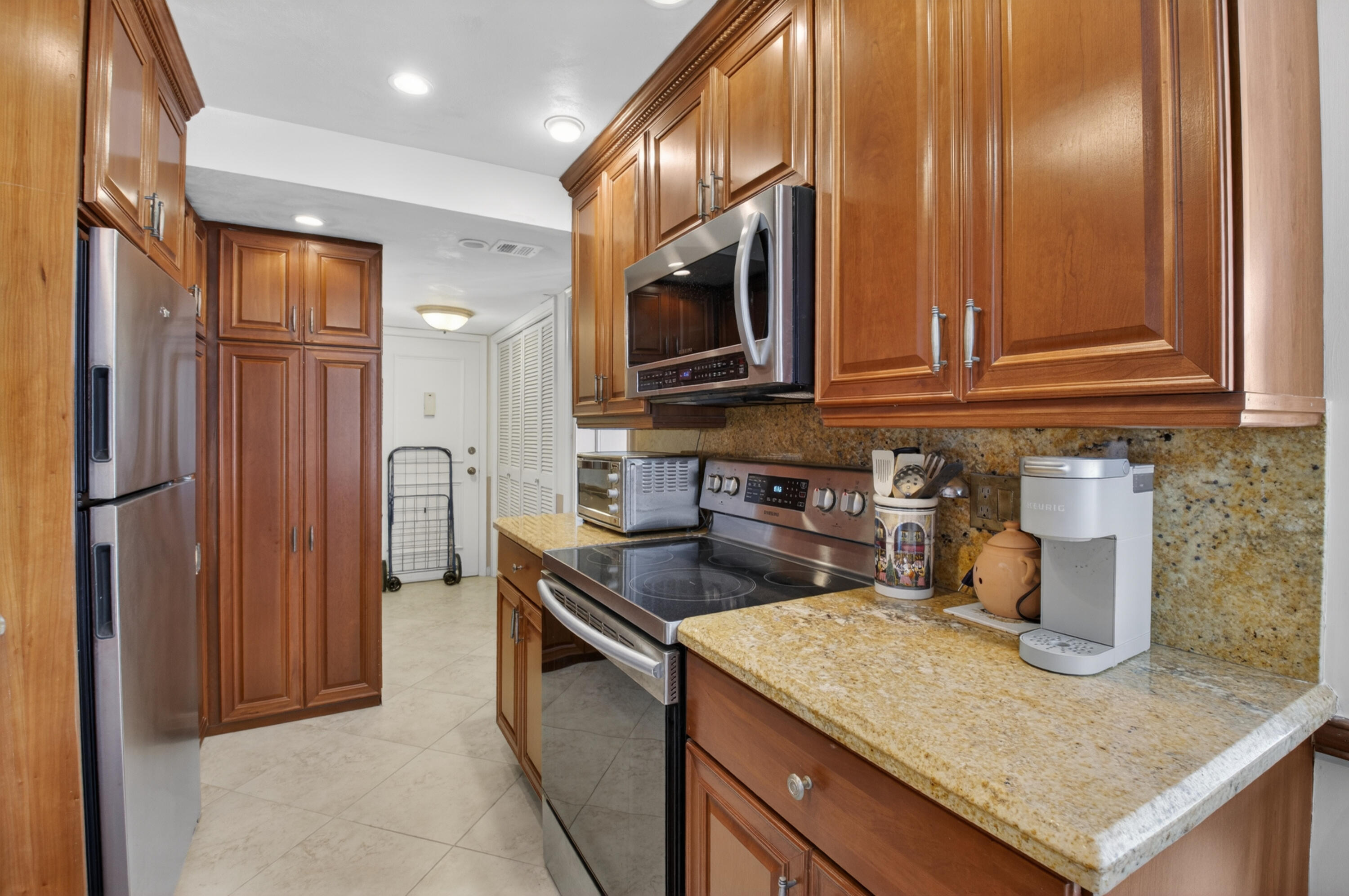 1180 South Ocean Boulevard, Unit 5C Boca Raton, FL 33432 - Photo 26 of 43 a kitchen with stainless steel appliances granite countertop a sink and a refrigerator