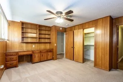 a view of an empty room with cabinet and a ceiling fan