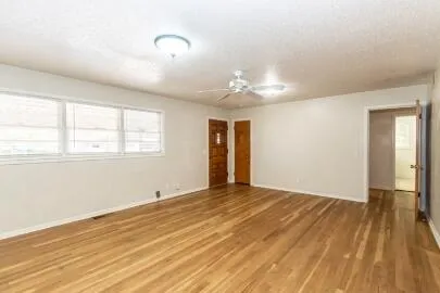 a view of an empty room with wooden floor and a window