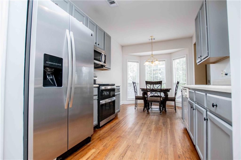 2657 Neighborhood Walk Villa Rica, GA 30180 - Photo 24 of 81 a kitchen with stainless steel appliances granite countertop a refrigerator stove microwave and white cabinets with wooden floor