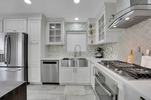 a kitchen with stainless steel appliances granite countertop a stove a refrigerator and a sink