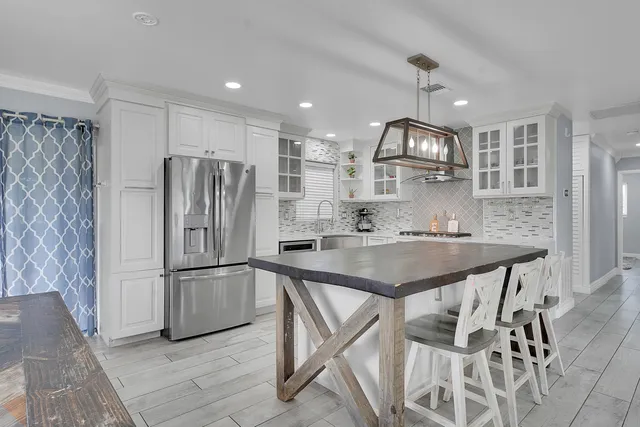 a kitchen with kitchen island stainless steel appliances cabinets a sink and a refrigerator