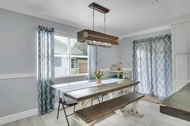a dining room with wooden floor a chandelier a wooden table and chairs