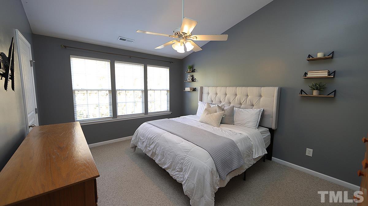 7626 Winners Edge Street Raleigh, NC 27617 - Photo 12 of 20 a spacious bedroom with a large bed and a chandelier