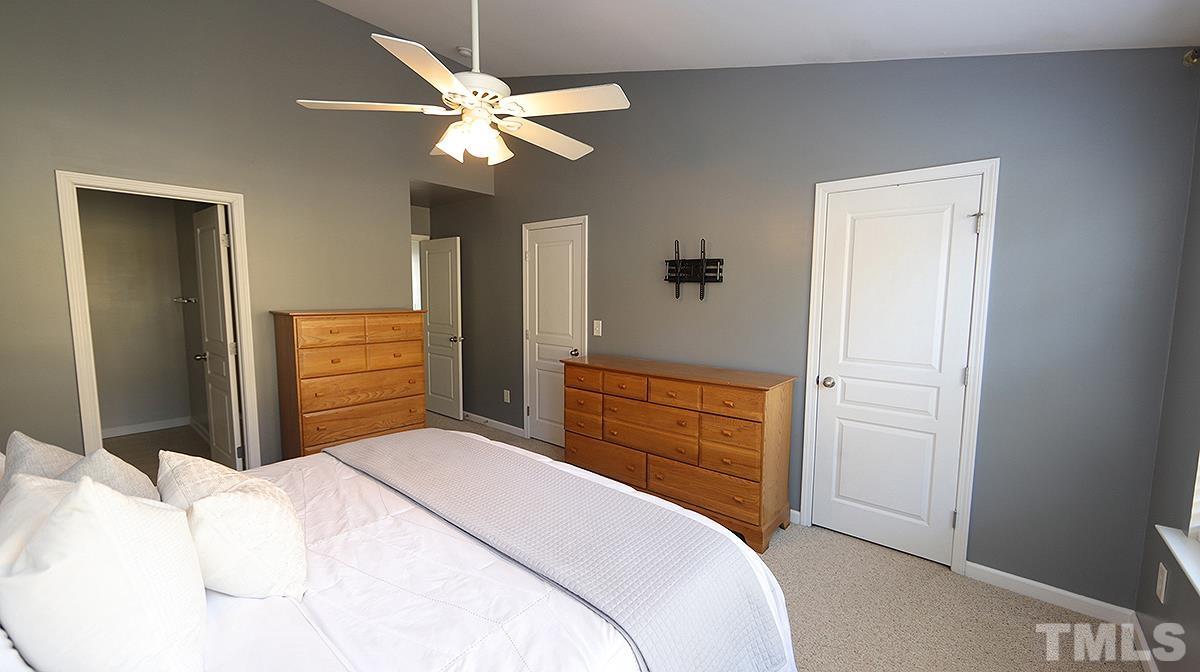 7626 Winners Edge Street Raleigh, NC 27617 - Photo 13 of 20 a bedroom with a bed and a chandelier