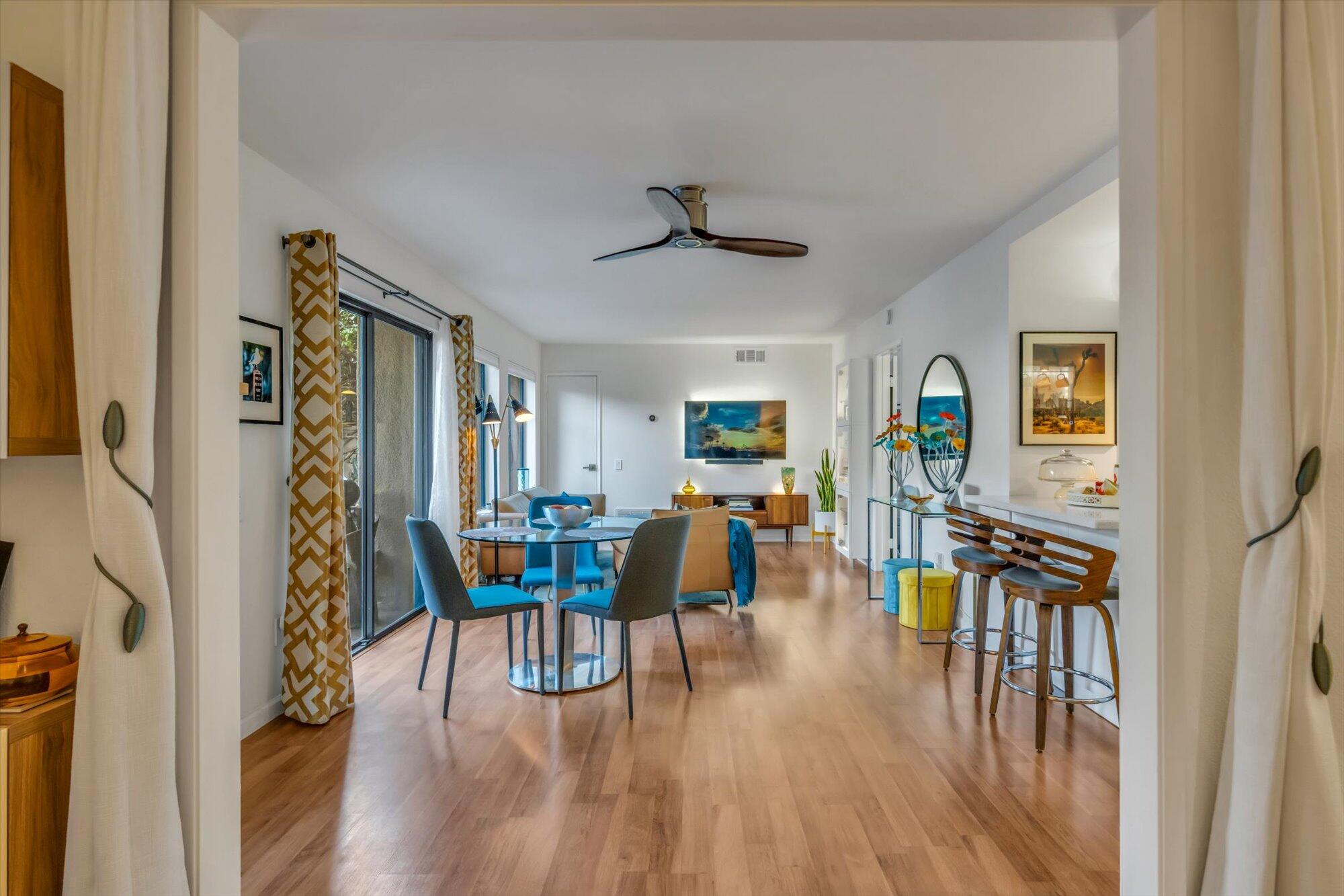 1100 East Amado Road, Unit 12B1 Palm Springs, CA 92262 - Photo 23 of 29 a dining room with wooden floor a chandelier a glass table and chairs