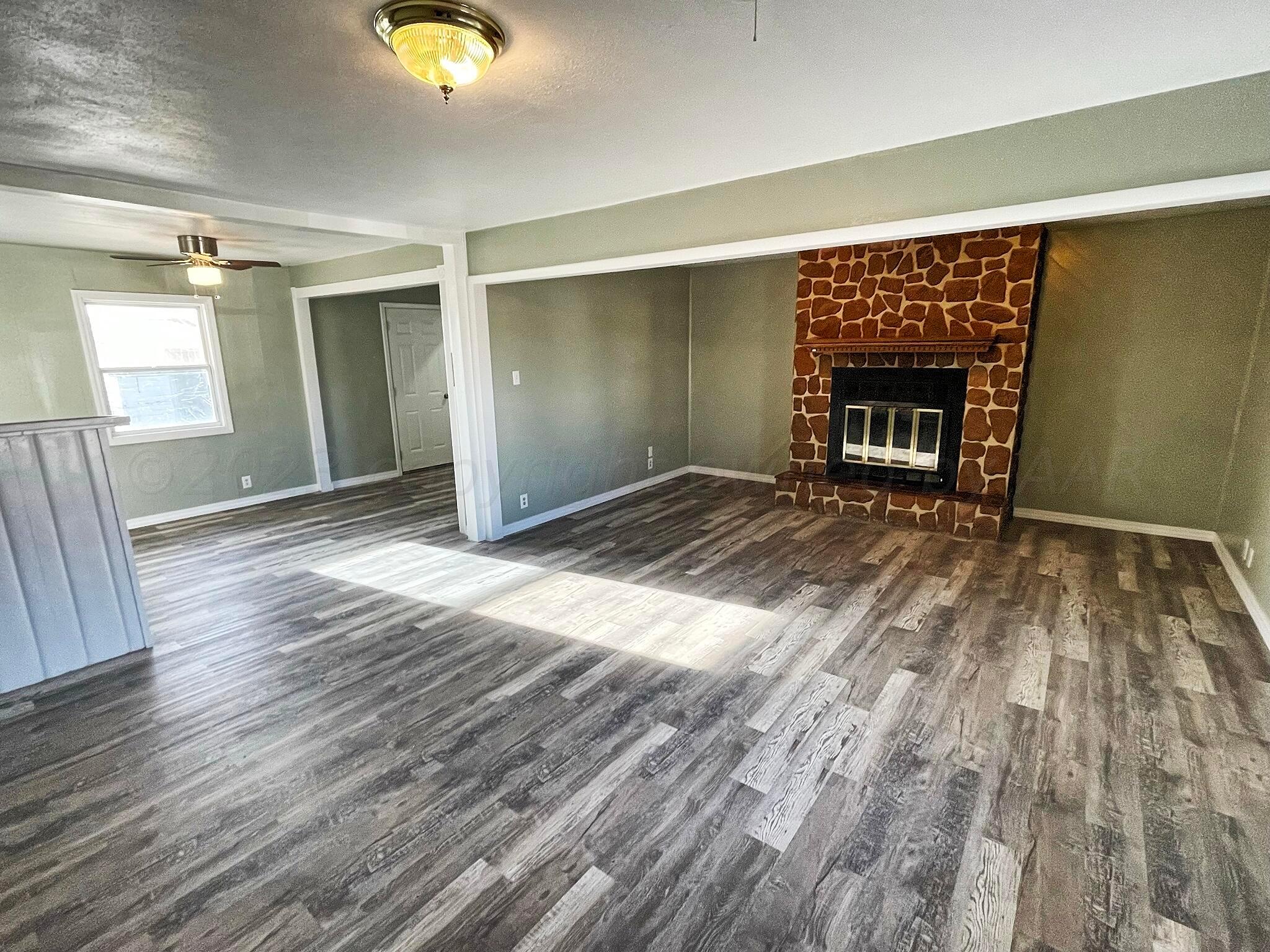 101 North Kentucky Street Perryton, TX 79070 - Photo 2 of 16 a view of an empty room with wooden floor and a fireplace