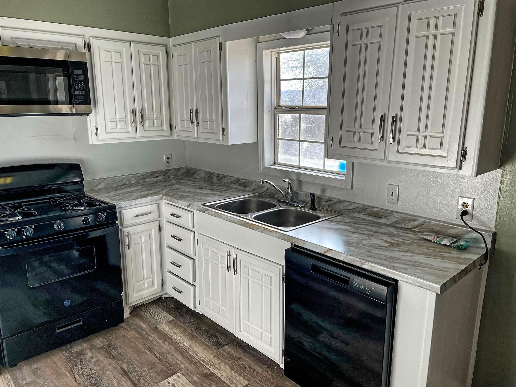 101 North Kentucky Street Perryton, TX 79070 - Photo 4 of 16 a kitchen with stainless steel appliances granite countertop a stove and a microwave