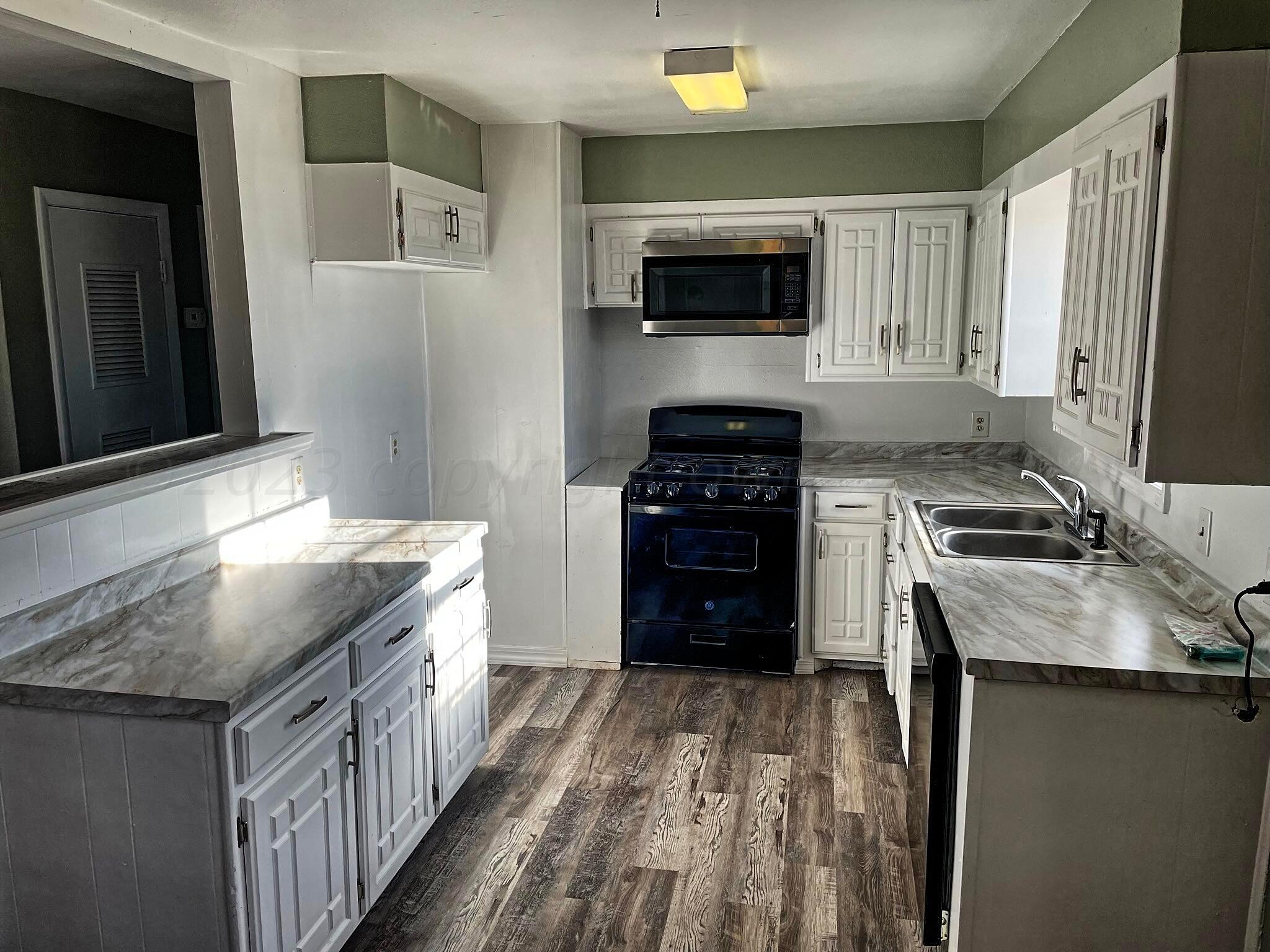 101 North Kentucky Street Perryton, TX 79070 - Photo 5 of 16 a kitchen with stainless steel appliances granite countertop a stove a sink and a microwave
