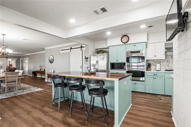 a kitchen with stainless steel appliances granite countertop a table chairs sink and cabinets