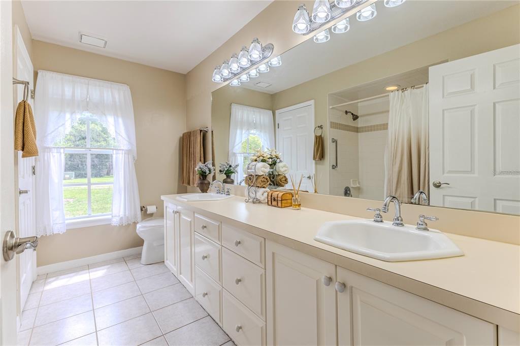 7512 Oak Tree Lane Spring Hill, FL 34607 - Photo 63 of 89 a spacious bathroom with a double vanity sink a mirror and a bathtub