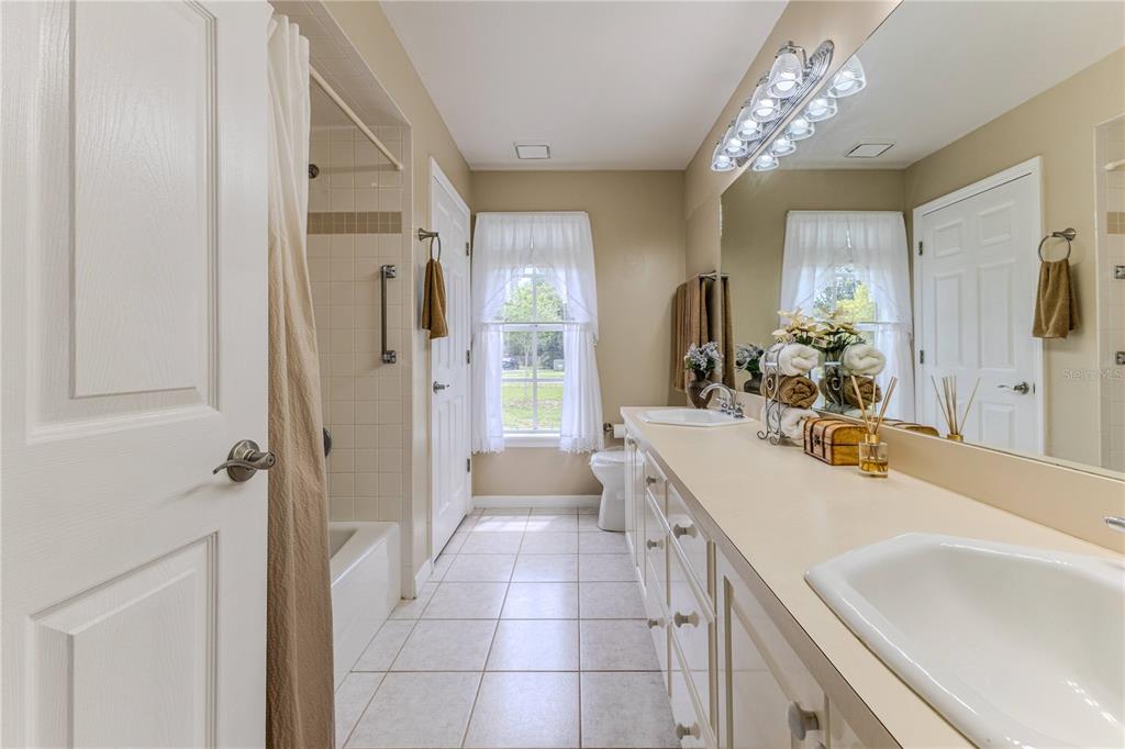 7512 Oak Tree Lane Spring Hill, FL 34607 - Photo 64 of 89 a spacious bathroom with a sink double vanity granite tub shower and a mirror