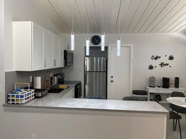 a kitchen with stainless steel appliances granite countertop a refrigerator a sink dishwasher and white cabinets with wooden floor