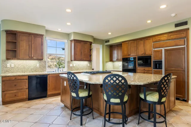 a kitchen with granite countertop a dining table chairs cabinets a sink and a stove