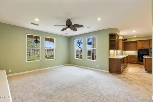 a view of an empty room with a window and a kitchen