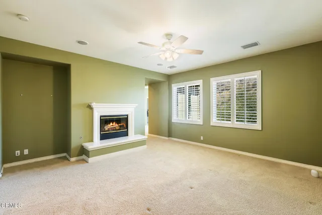 a view of an empty room with a window and fireplace