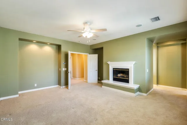 a view of a livingroom with a fireplace a ceiling fan and a window