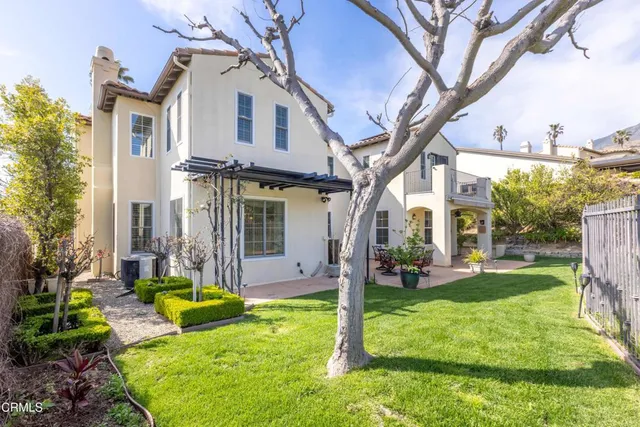 a view of a white house next to a yard with big trees