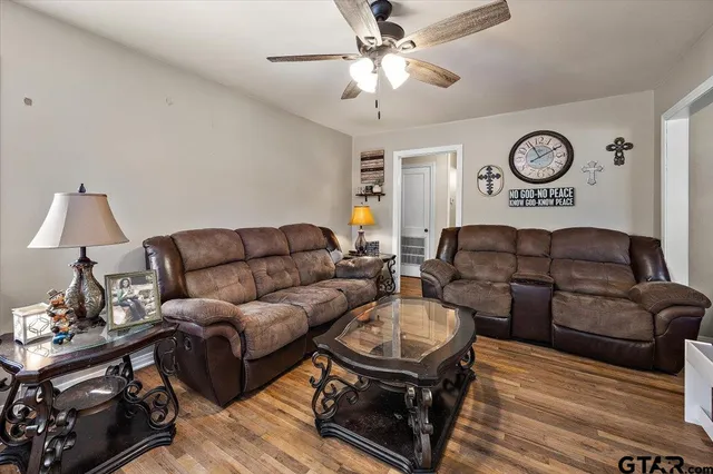 a living room with furniture a clock and a ceiling fan